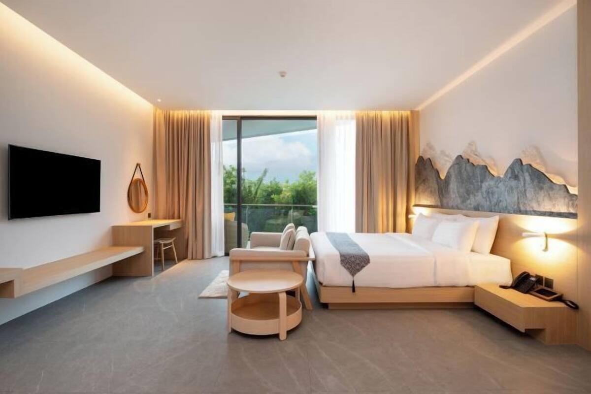 A modern hotel room with a bed, desk, chair, and a TV.