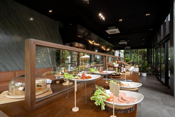 A modern dining area with glass display cases, wooden tables, and a view of greenery outside.