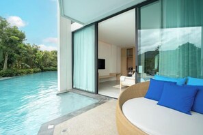 A modern room with a large glass door leading to a pool, a sofa with blue cushions, and a flat-screen TV. - Timberton Resort Khaoyai (Pak Chong)