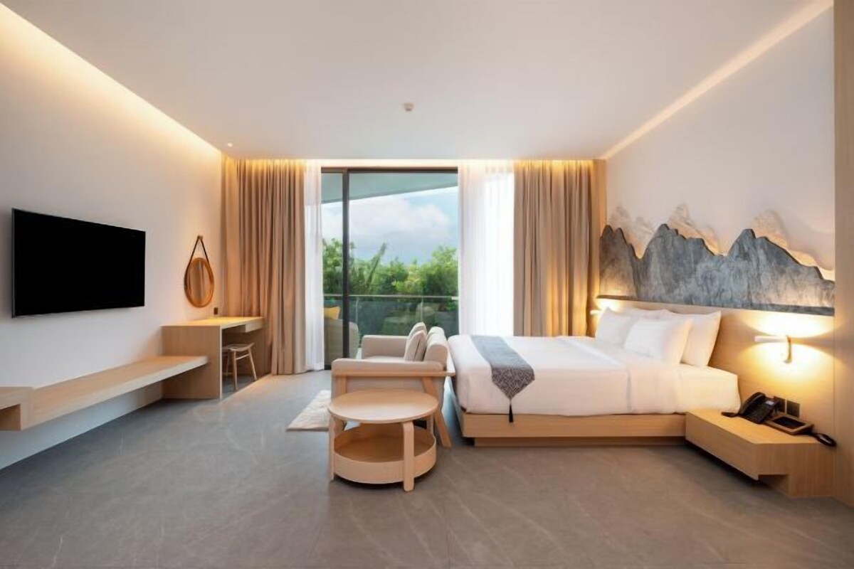 A modern hotel room with a bed, desk, chair, and a TV.