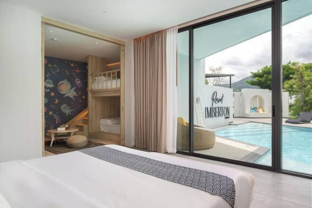 A bedroom with a large bed, a view of a swimming pool, and a room with a mural.