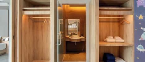 A compact, modern bathroom with built-in wooden shelves, a mirror, and a sink.