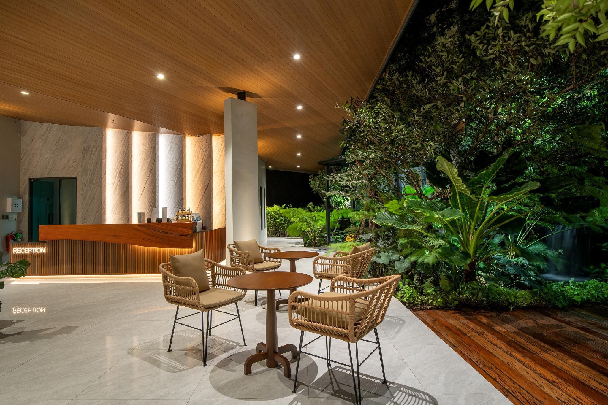 A reception area with a wooden reception desk, wicker chairs, and a lush indoor garden.