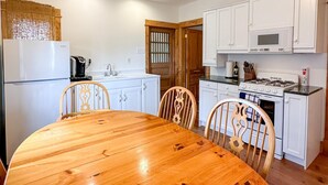 A compact kitchen with white cabinets, a wooden dining table, and a built-in oven. - Stunning Cottage across for public Bayshore beach (Grand Marais)