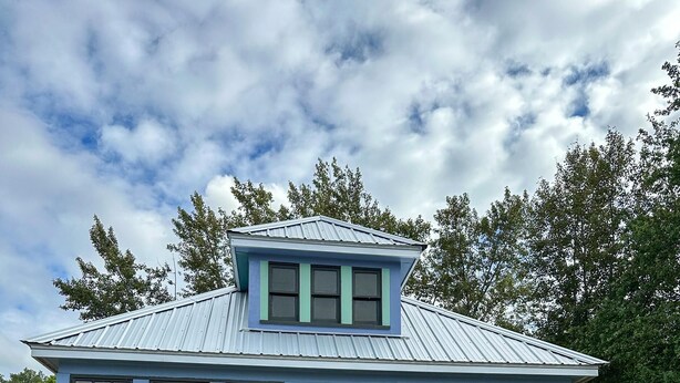 A small, single-story building with a blue and green exterior, a yellow door, and a sign reading "E21831". - Stunning Cottage across for public Bayshore beach (Grand Marais)