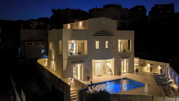 Un edificio moderno de varios pisos con piscina, asientos exteriores y una escalera que lleva a la entrada.