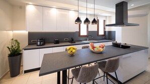 Una cocina moderna con una isla central, iluminación colgante y una estufa empotrada.