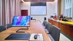 A conference room with a large table, a projector screen, a computer monitor, a keyboard, and a mouse. - Hongdou Lanting Inn (Renhua)