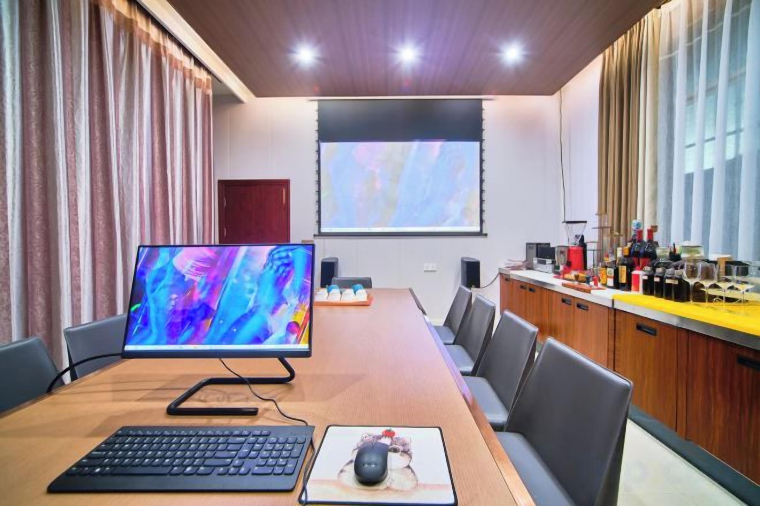 A conference room with a long table, chairs, a projector screen, and a coffee station.