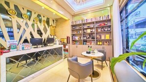 A modern reception area with a desk, chairs, and a bookshelf. - Hongdou Lanting Inn (Renhua)