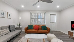A modern living room with a sofa, coffee table, and ottomans.