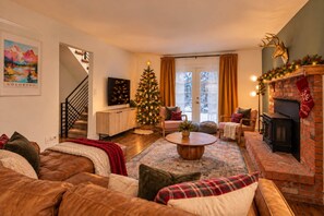 A cozy living room with a fireplace, a Christmas tree, and a sofa.
