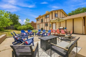 Un patio al aire libre con sillones de descanso, una mesa y una zona de barbacoa.