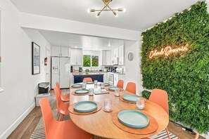 A modern kitchen with white cabinets, a central island, and a neon sign on the wall.