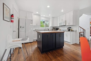 Une cuisine moderne avec des meubles blancs, un îlot central noir et un plancher en bois.