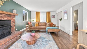 A living room with a fireplace, a sofa set, a coffee table, and a patterned rug. - Themed Bedrooms, Movie Room & Firepit Yard (Westminster)