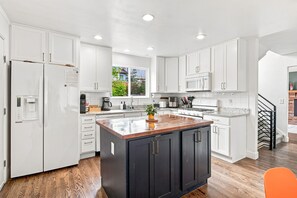 A modern kitchen with white cabinetry, a central island, and a stainless steel range hood.