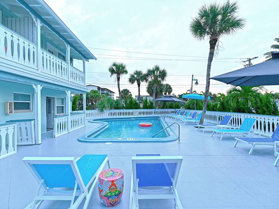 A pool area with a rectangular pool, lounge chairs, and a decorative table.