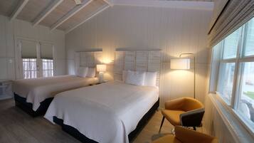 A hotel room with two beds, a window with curtains, a ceiling fan, and a chair.