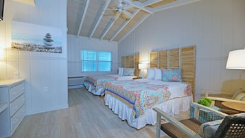 A bedroom with two beds, a ceiling fan, a window with blinds, and a bedside table with a lamp.