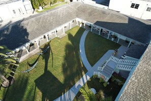 An aerial view of a courtyard with a covered seating area, a hammock, and a small garden.