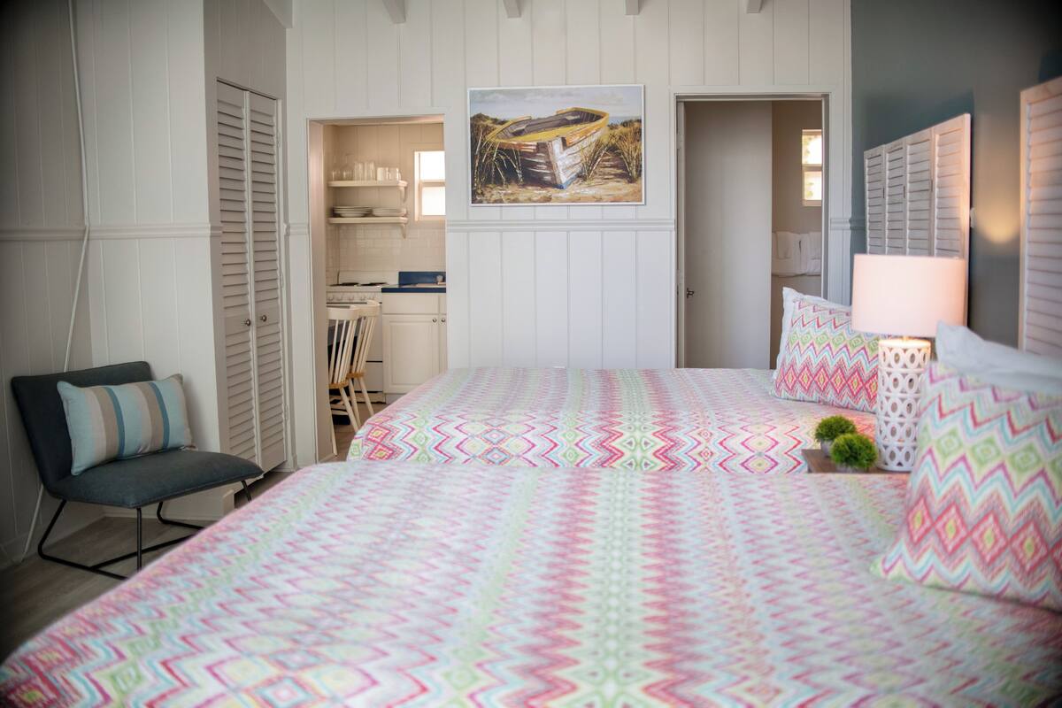 A bedroom with a bed, a chair, a painting, and a closet.