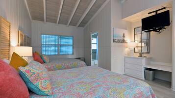 Un dormitorio con dos camas, televisión, cómoda y ventana con persianas.