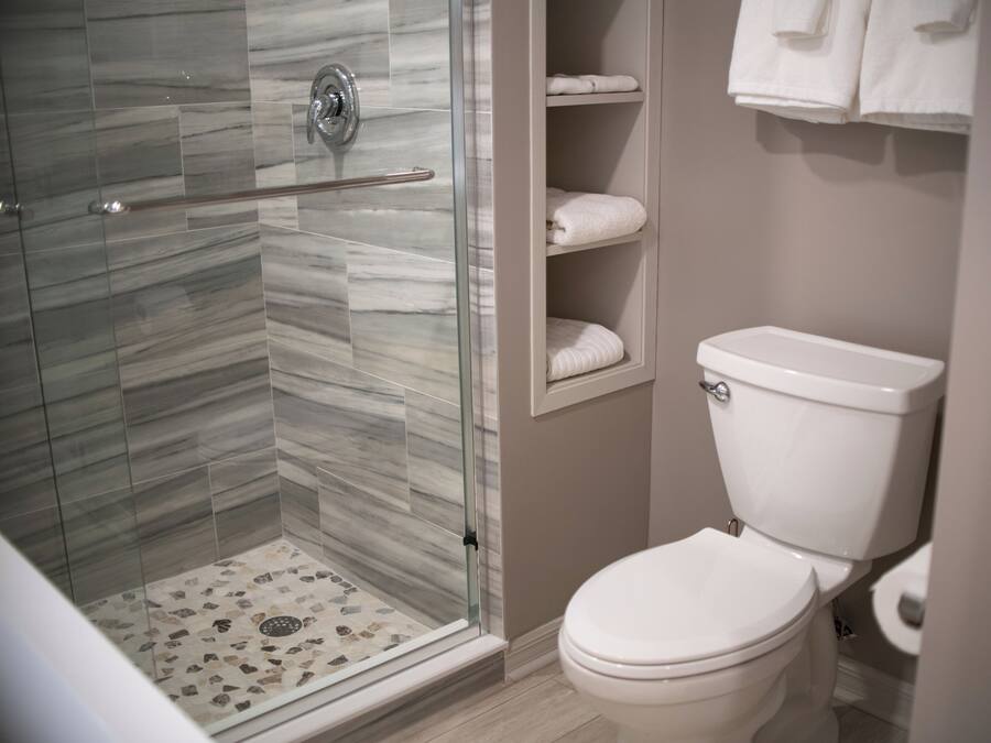 Ein Badezimmer mit einer Duschkabine, einer Toilette und einem Ablagefach mit Handtüchern.