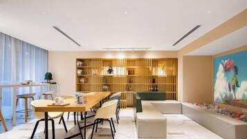 A modern interior with a dining area, a bookshelf, and a colorful painting.