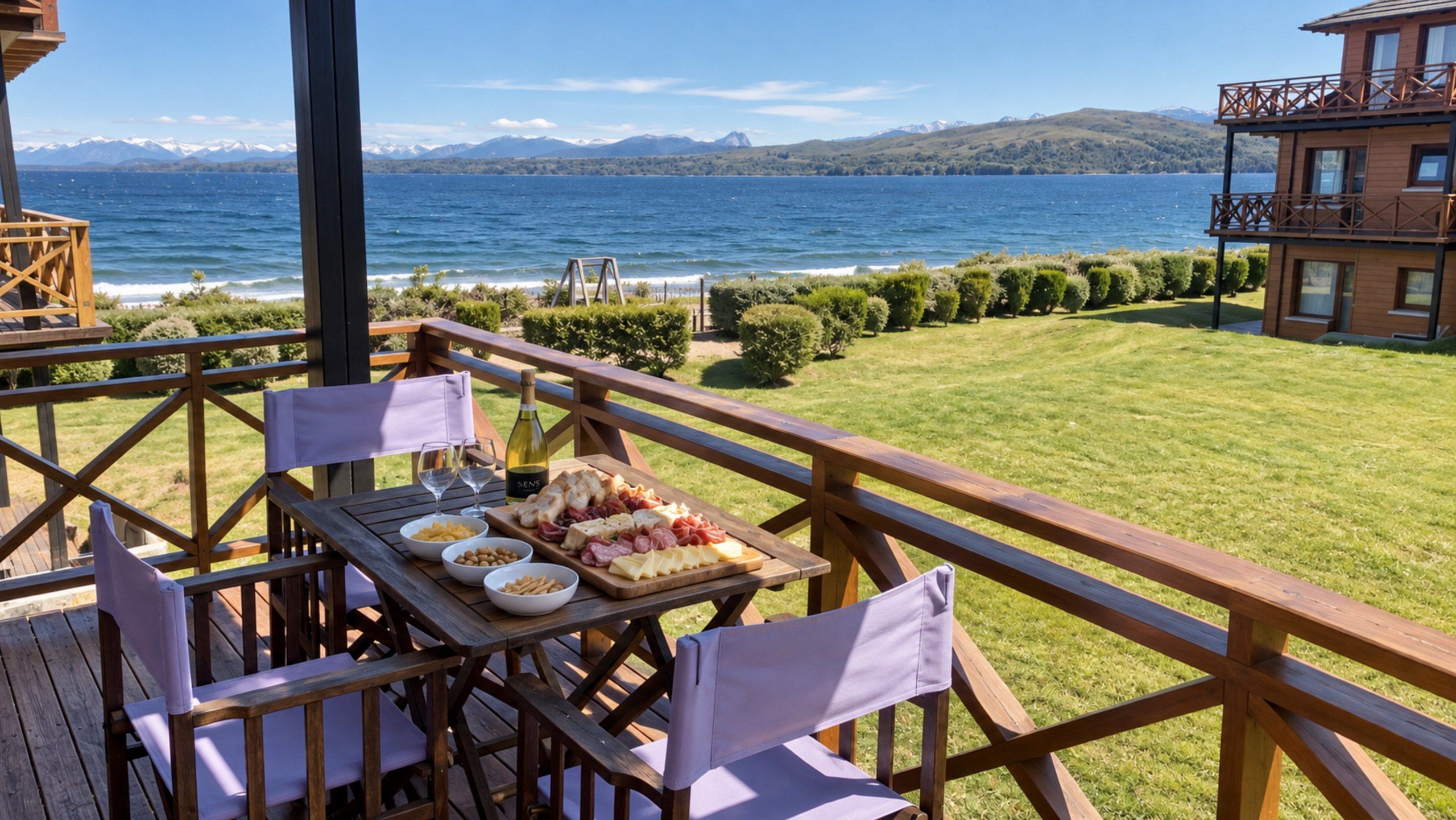 A wooden deck with a table set for a meal, overlooking a lake with mountains in the distance.