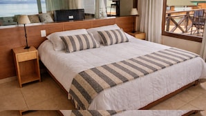 A bedroom with a large bed, wooden headboard, bedside tables, and a view of the outdoors. - Crystal Suite Loft 2nd Floor Lake Front Bariloche (Dina Huapi)