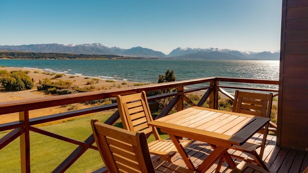 A wooden deck with a table and chairs overlooking a lake and mountains. - Nahuel 2nd Floor Lake View Dina Huapi Bariloche (Dina Huapi)