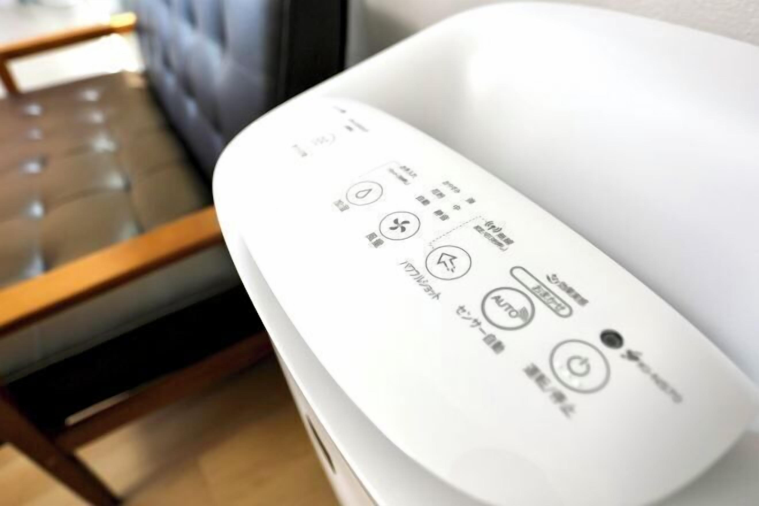 A remote control with Japanese symbols and text, placed on a white surface.