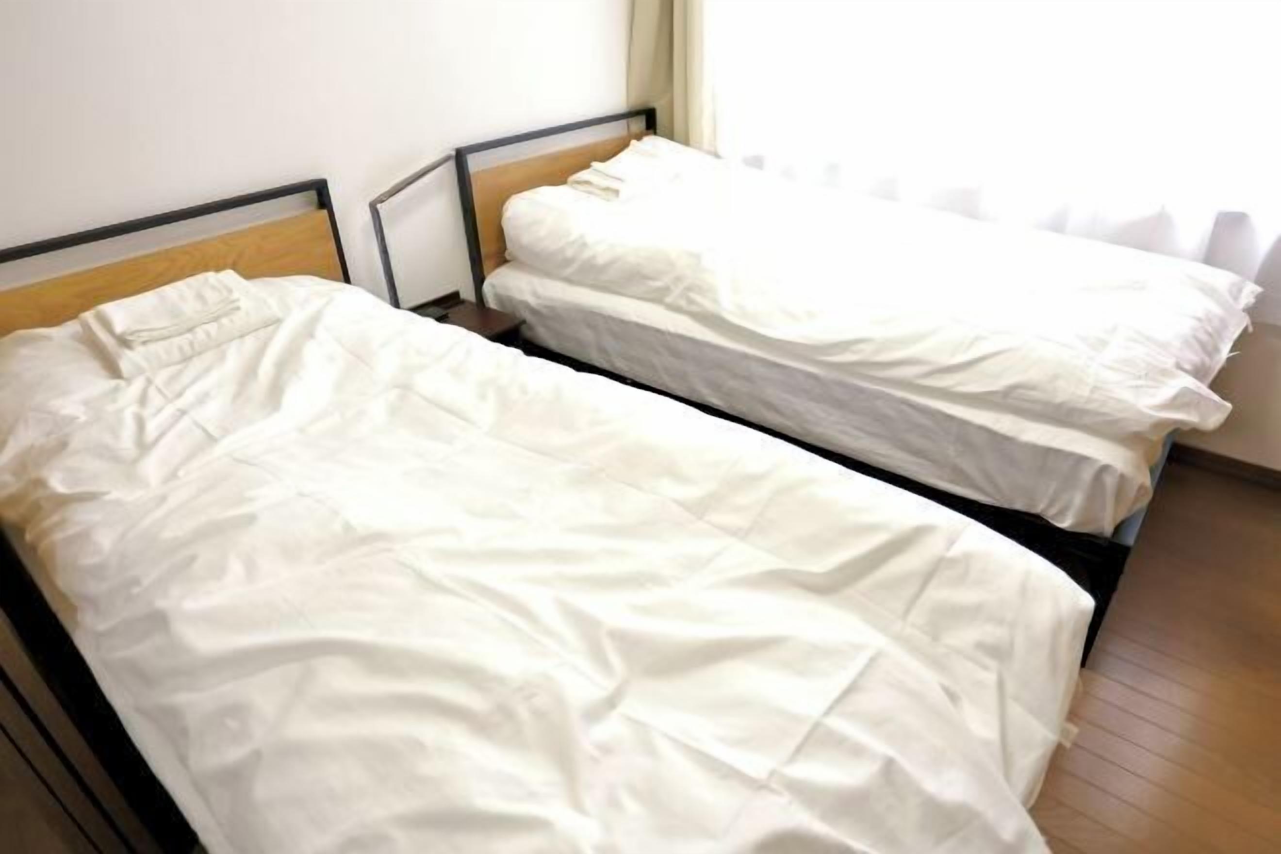 A room with two single beds, wooden headboards, and a window with curtains.