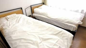 A room with two single beds, wooden headboards, and a window with curtains.