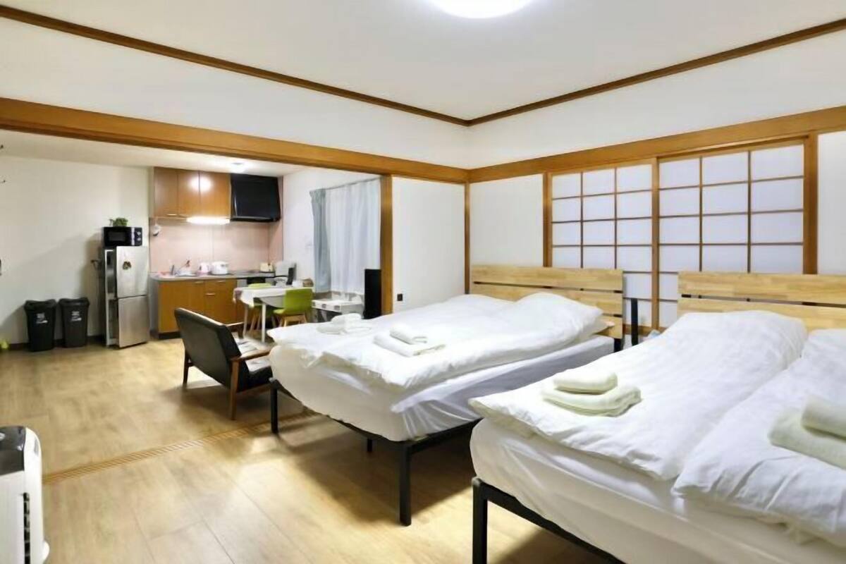 Ein Hotelzimmer mit zwei Betten, einer Küchenzeile, einem Essbereich und einer Schiebetür.