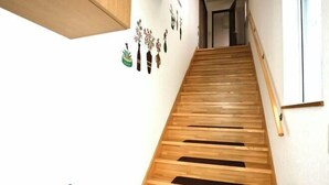 Una scala in legno con corrimano, una parete con adesivi decorativi e un pavimento in legno.