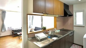 Una cucina compatta con mobili in legno, un lavello in acciaio inossidabile e una finestra sopra il piano di lavoro.