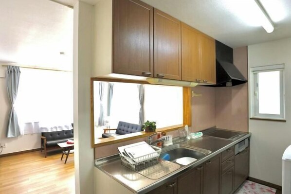 A compact kitchen with wooden cabinets, a stainless steel sink, and a window above the counter. - Dream Tree Sapporo City electricity 0 minutes walk 1 minute supermarket (Sapporo)