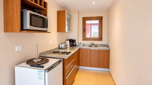 Una cocina compacta equipada con microondas, tostadora, cafetera y un refrigerador pequeño.