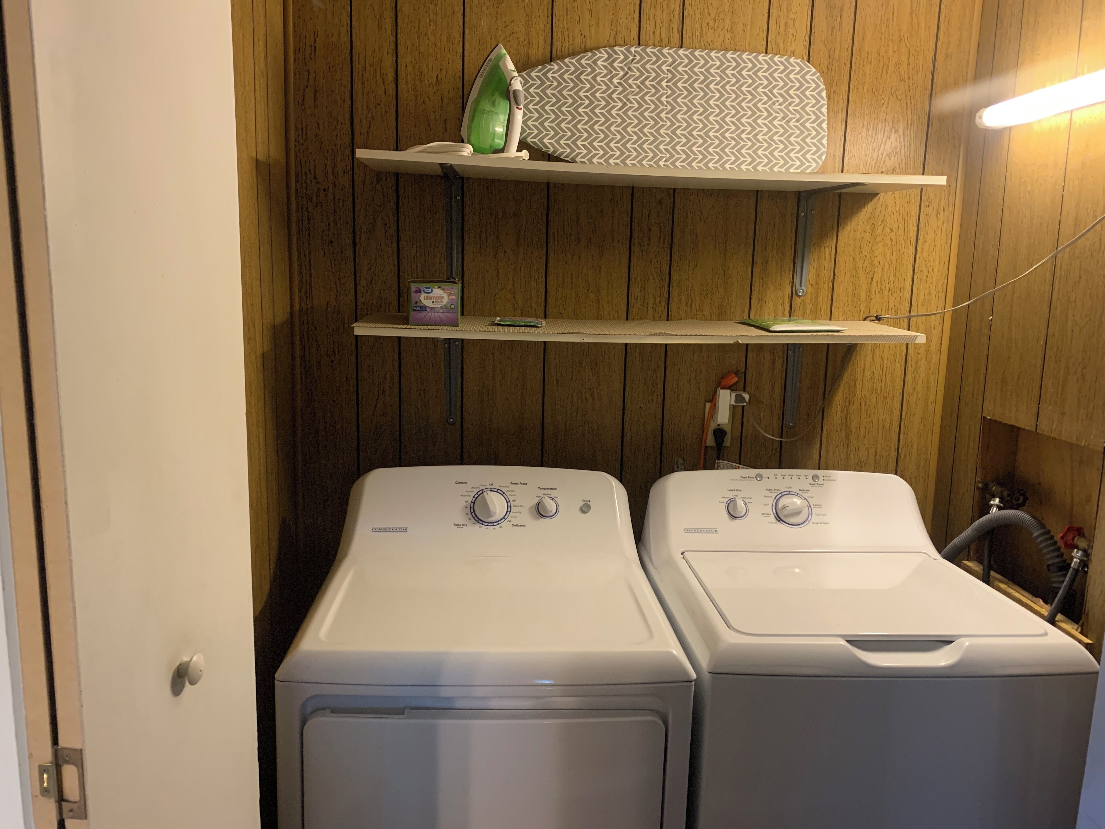A laundry area with two front-loading washers and a shelf above them.
