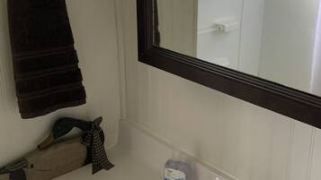 Une salle de bain avec un lavabo blanc, un robinet foncé, un porte-serviettes avec une serviette marron, une décoration en forme de canard et un flacon de savon pour les mains.