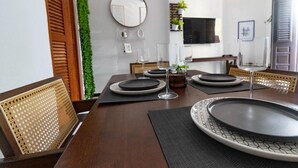 Un coin repas avec une table en bois dressée pour quatre personnes, entourée de chaises en osier.
