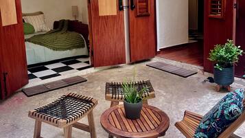 Een kamer met een bed, een houten deur, een kleine tafel met een plant en een stoel met een gestreept kussen.