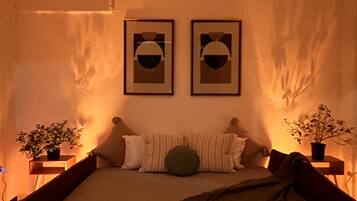 Een slaapkamer met een bed, twee ingelijste foto's aan de muur en twee potplanten op nachtkastjes.