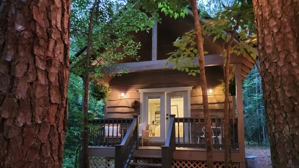 Una baita con una veranda in legno, una scala e un'uscita che conduce all'interno.