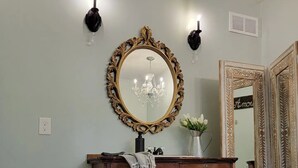 Un comò in legno con cassetti e uno specchio, un lampadario e due applique.