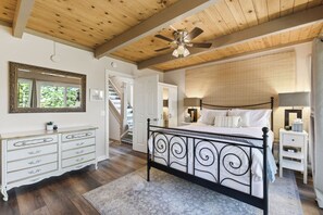 A bedroom with a bed, dresser, and a ceiling fan.