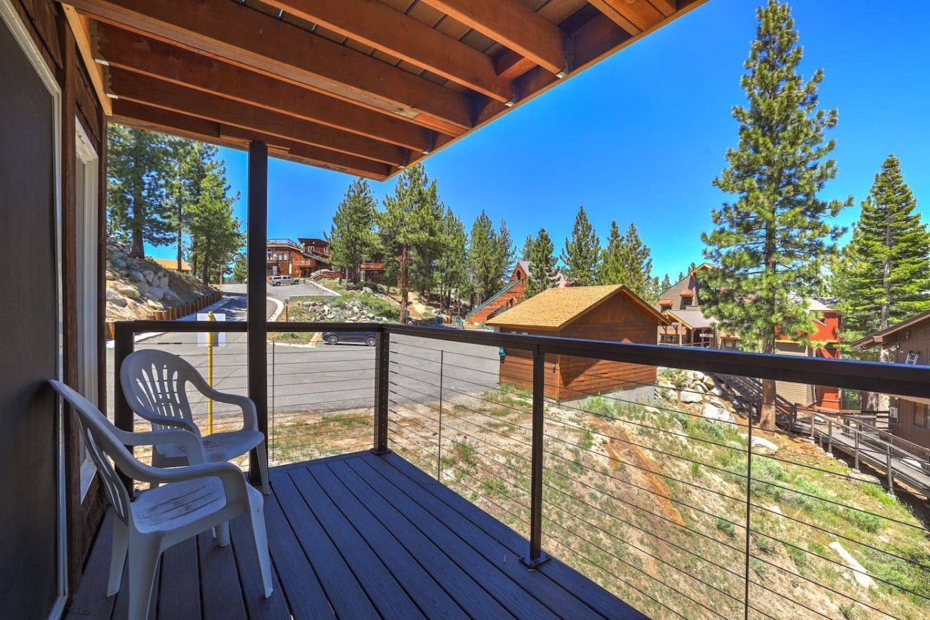A wooden deck with a view of a residential area, a small wooden structure, and a chair.