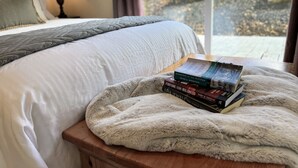 A neatly made bed with a fluffy blanket and a stack of books on a bedside table. - Killington Retreat | Deck-Fire Pit-Mountain Views! (Clarendon)